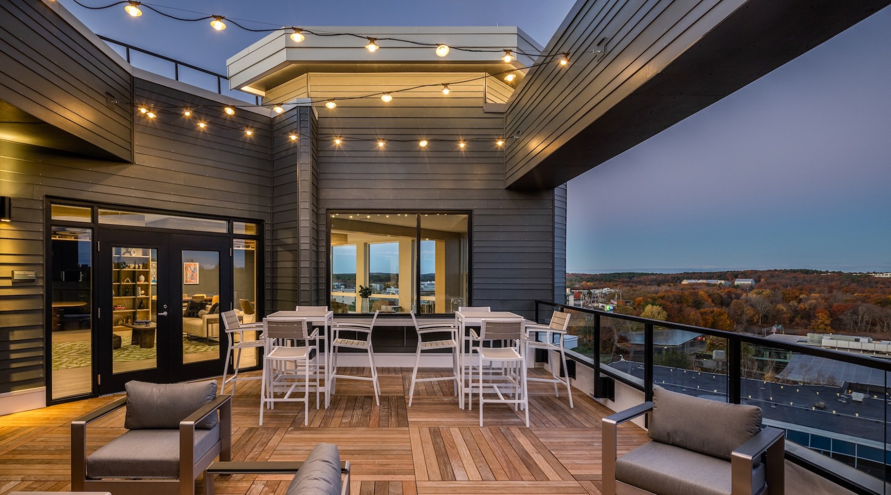 The rooftop lounge at The 305 apartments in Waltham, MA, featuring outdoor seating and a view of the town.
